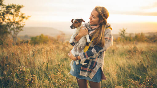woman holding jack russell in a field