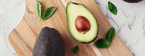 Wooden table with avocados and basil on marble stone