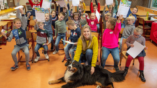 A classroom of kids with their teacher and a dog